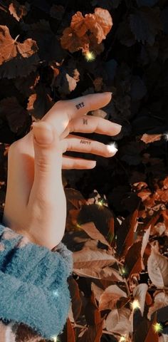 a person's hand with tattoos on it in front of some leaves and lights