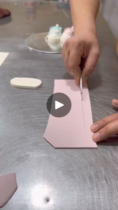 a person cutting up a piece of paper on top of a metal table with scissors