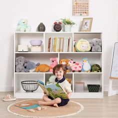 a young boy sitting on the floor reading a book in front of a bookshelf