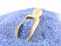 a wooden spoon sitting on top of some blue glittered material with a white background