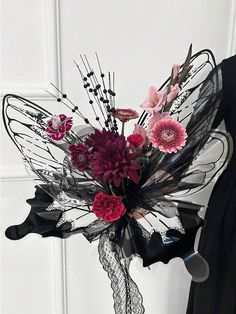 a vase filled with lots of flowers on top of a table next to a white wall