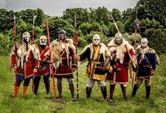 a group of men dressed in costume standing next to each other on top of a lush green field