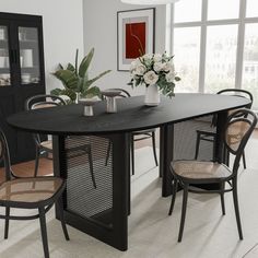 a dining room table with chairs and vases on it's centerpiece, in front of large windows