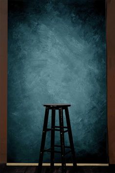 a black stool sitting in front of a blue wall