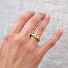 a woman's hand wearing a gold ring with a diamond on the middle finger