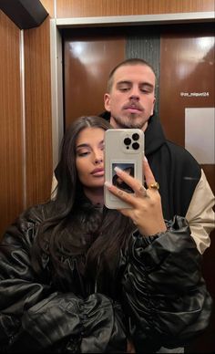 a man and woman taking a selfie in front of a mirror with their cell phone