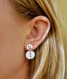 a close up of a person's ear wearing snowman earrings