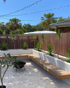 a wooden bench sitting in the middle of a patio next to a planter filled with potted plants