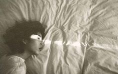 a black and white photo of a woman laying in bed with her head on the pillow