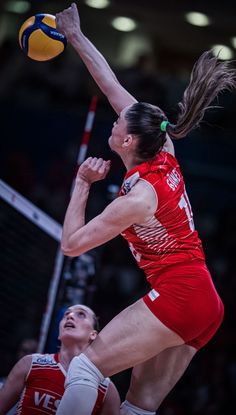 a female volleyball player jumping up to hit the ball