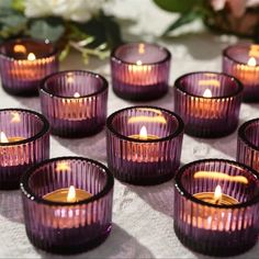 many purple glass candles sitting on top of a table