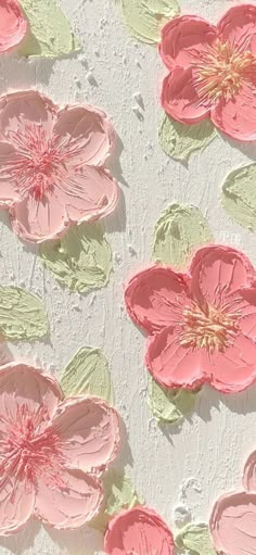 some pink flowers and green leaves on a white surface