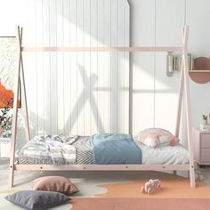 a child's bed with pink and blue sheets, pillows and toys on the floor