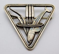 We offer a wonderful Georg Jensen Sterling Silver Brooch/Pin in the scarce pattern number 257. This a wonderful Art Deco piece that was designed by Arno Malinowski in the 1930's and is consists of a diving Dolphin with cattails in a triangular frame. This lovely piece is in superb condition, the sturdy rollover pin is secure and will prevent loss. As the photos demonstrate, this lovely piece has a slight patina. The Brooch measures 1 5/8's inches on each side and weighs approx. 11 grams. We beli Collectible Art Nouveau Hallmarked Brooch, Art Deco Engraved Brooch For Formal Occasions, Art Deco Engraved Brooches For Formal Occasions, Art Deco Engraved Brooches For Formal Events, Modernist Silver Jewelry, Georg Jensen Jewelry, Bijoux Art Deco, Lapel Brooch, Silver Brooch Pin