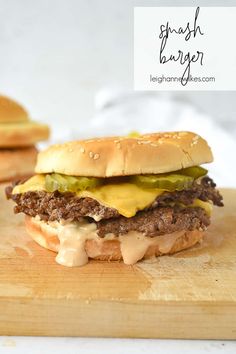 a cheeseburger on a cutting board with two burgers in the background