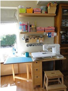 a sewing machine sitting on top of a table next to a wooden shelf filled with craft supplies