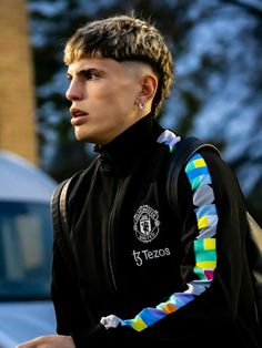 a young man wearing a black jacket with multicolored stripes on the sleeves and shoulder