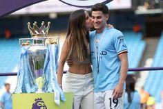 two people kissing each other in front of a trophy and banner with the number 19 on it