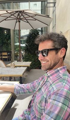 a man wearing sunglasses sitting at an outdoor table