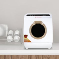 a white washer sitting on top of a kitchen counter next to plates and utensils