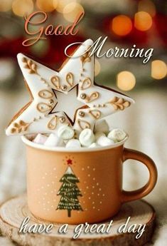 a coffee cup with marshmallows and a star on it is sitting in front of a christmas tree