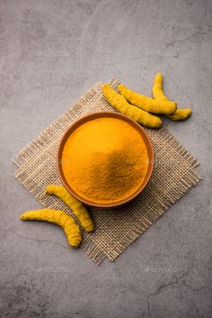 a bowl filled with yellow powder next to bananas on top of a cloth covered table