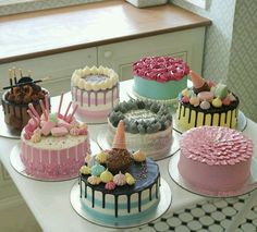 a table topped with lots of cakes covered in different types of frosting and toppings