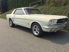 an old car is parked on the side of the road in front of some bushes