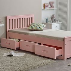 a child's bed with pink drawers in the middle and a stuffed animal on the floor