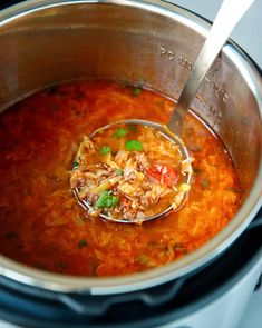 a ladle full of soup is being stirred in the pot on the stove top