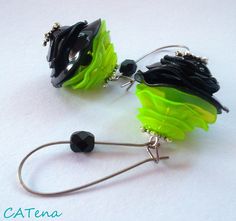 two black and green earrings with silver hooks on white background, one is dangling from the hook