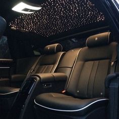 the interior of a car with black leather seats and lights on the ceiling above it