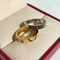 two gold and silver rings sitting in a red box