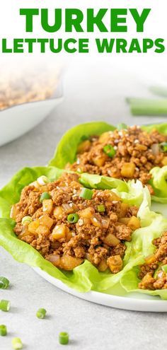 two lettuce wraps filled with meat and topped with green onions on a white plate