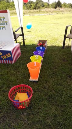 several buckets and cups on the grass near an ice cream stand with balloons in the background