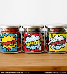 three glass jars filled with colorful candies sitting on top of a wooden table next to each other