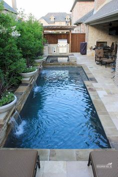 an outdoor swimming pool surrounded by patio furniture and landscaping area, with water feature in the middle