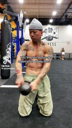 a shirtless man holding a kettle in a gym