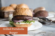 a sandwich with meat and lettuce sitting on a plate next to bread rolls