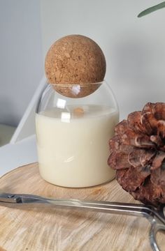 a pine cone sitting on top of a wooden table next to a glass jar filled with milk