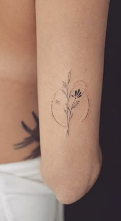 a woman's arm with a small flower tattoo on the left side of her body