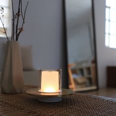 a white candle sitting on top of a table next to a vase with flowers in it