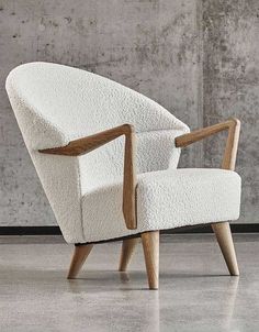 a white chair sitting in front of a wall with concrete walls behind it and a wooden armrest