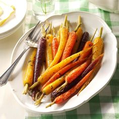 there is a white plate with carrots and other vegetables on it, along with silverware