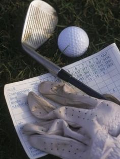 two golf balls and a pair of gloves laying on the grass next to each other