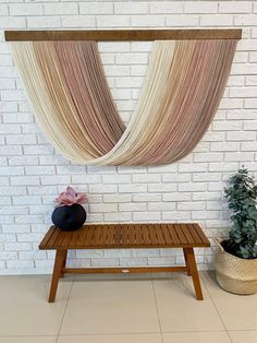 a wooden bench sitting in front of a white brick wall with curtains hanging above it