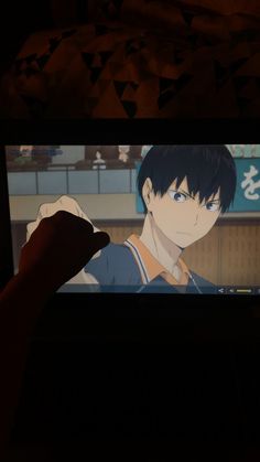 a person is playing an anime on the tv screen with their hand in front of them