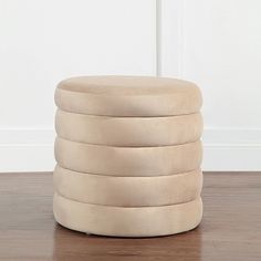 a stack of round stools sitting on top of a hard wood floor next to a white wall