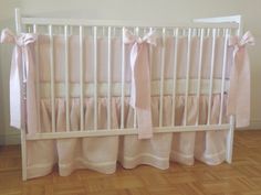 a baby crib with pink and white bedding on top of wooden flooring