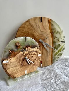 two clocks made out of wood and glass on top of white sheeted paper next to each other